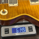 Close-up of a sunburst electric guitar body resting on a digital scale showing a weight of 6 lbs 14.9 oz.