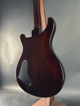 Glossy dark brown electric guitar body on a reflective surface with a neutral background