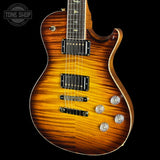A close-up of a Fender electric guitar body in a sunburst finish, showing the wood grain, pickups, and control knobs against a black background with a Tone Shop watermark.
