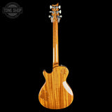 A high-gloss electric guitar shown from the back, featuring a flamed maple wood body and neck with a natural honey-orange finish, set against a solid black background with a Tone Shop watermark in the top-left corner.