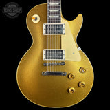 A gold glitter electric guitar body with a cream pickguard, chrome hardware, and a dark fretboard, shown against a black background with a Tone Shop watermark in the top left corner.