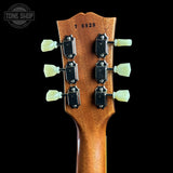 Close-up of the headstock of a guitar, showing six tuning pegs, black tuning machines, and the serial number 76939 on a black background. A Tone Shop watermark is visible in the top left corner.