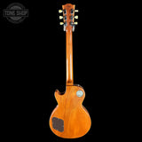 A 1956 Gibson Les Paul Custom electric guitar shown from the back, featuring a warm honey-amber wood finish, a brown pickguard, and a silver chrome tailpiece, set against a solid black background with a Tone Shop watermark in the top-left corner.