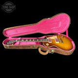 A sunburst electric guitar inside an open vintage-style hard case with a bright pink velvet interior, shown against a black background. A Tone Shop watermark is visible in the top-left corner.