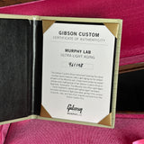 A Gibson Custom Certificate of Authenticity insert for a Murphy Lab Ultra Light Aging instrument, displayed inside an open gold-lined presentation box on a pink velvet surface.