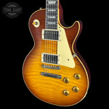 A classic electric guitar with a natural sunburst finish, cream pickguard, and gold hardware, shown against a solid black background with a Tone Shop watermark in the top left corner.