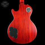 The back of a red electric guitar with a glossy cherry-red finish, featuring a black pickguard and a gold 'Gibson' logo badge on a black background.