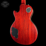 The back of a Gibson Les Paul Custom electric guitar with a vibrant red cherry finish, featuring a black pickguard and a silver metal plate on a black background.