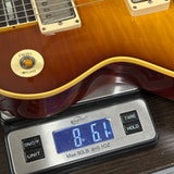 A close-up of a guitar body resting on a digital scale displaying 8.61 lbs.
