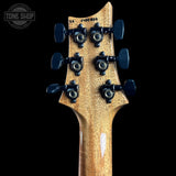 Close-up of the back of a six-string electric guitar headstock, showing six black tuning pegs and a natural wood grain finish, set against a solid black background with a Tone Shop watermark in the top left.