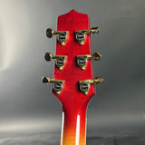 Close-up of a red guitar headstock with tuning pegs on a gray background