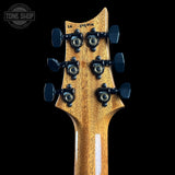 Close-up of the headstock of an electric guitar against a solid black background, showing six black tuning pegs and a glossy natural wood grain finish. A 'TONE SHOP' watermark is visible in the top left corner.