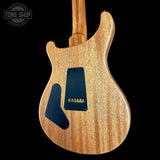 The back of an electric guitar with a natural wood finish and black pickguard, shown against a solid black background with a Tone Shop watermark in the top left corner.