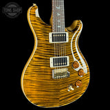 A close-up of an electric guitar body with a natural figured maple wood finish showing prominent grain patterns, set against a solid black background.