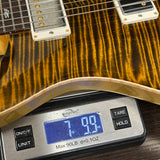 Close-up of a guitar body resting on a digital scale, showing the scale reading 7.90 oz.