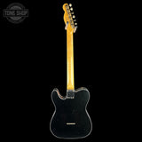 A black electric guitar shown from the back against a solid black background, featuring a natural maple neck and a Tone Shop watermark in the upper left corner.