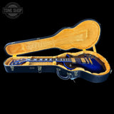 Blue electric guitar in an open hardshell case with 'Tone Shop' branding.