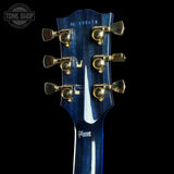 Blue guitar headstock with tuning pegs on a black background, featuring the Gibson logo.