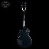 A black electric guitar shown from the back against a solid black background, with a Tone Shop watermark in the upper left corner.
