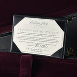 A close-up of a black leather guitar case opening to reveal a Certificate of Authenticity card from Custom Shop and C.F.
