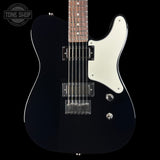 A black electric guitar with a white pickguard and chrome hardware, shown against a solid black background. A Tone Shop logo is visible in the top-left corner.