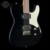 A black electric guitar with a white pickguard, dual humbucker pickups, and chrome hardware, shown against a solid black background with a Tone Shop watermark in the top left corner.