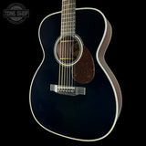 A close-up of an acoustic guitar body against a black background, featuring a glossy dark blue finish, white binding, a brown pickguard, and a silver bridge. A Tone Shop logo is visible in the top-left corner.