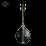 A black mandolin with a glossy finish, featuring gold-toned tuning pegs and a white bridge, shown against a solid black background with a Tone Shop logo in the top-left corner.