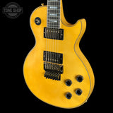 Yellow electric guitar with a black pickguard on a black background, featuring 'Tone Shop' branding.