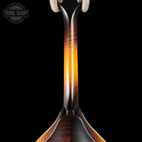 Close-up of the neck and lower body of a mandolin against a solid black background, showing a glossy natural wood finish with warm amber and dark brown grain patterns. A circular 'TONE SHOP' watermark is visible in the top-left corner.