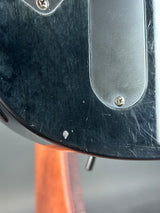 Close-up of a guitar with a black pickguard and wooden neck.