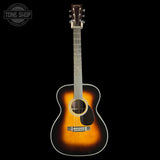 A classic acoustic guitar with a sunburst finish, featuring a dark brown outer edge fading to a bright amber-orange center, set against a solid black background.