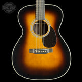 An acoustic guitar with a classic sunburst finish, featuring a bright orange center fading to a dark black edge, shown against a solid black background.