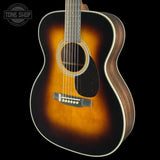 A classic acoustic guitar with a sunburst finish, featuring a dark brown outer edge fading to a warm amber-orange center, set against a solid black background.