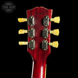 Close-up of a red guitar headstock with tuning pegs on a black background, featuring 'Tone Shop' branding.