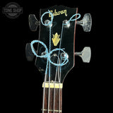 Gibson bass headstock with tuning pegs and strings on a black background