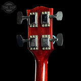 Close-up of a red guitar headstock with tuning pegs on a black background, featuring 'Tone Shop' logo.