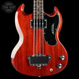 Red electric bass guitar with a black pickguard on a black background, featuring the Tone Shop logo.
