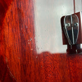 Close-up of a guitar's wooden body with a metal tuning peg.
