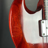 Close-up of a red electric guitar with a white pickguard on a dark background