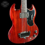 Red electric bass guitar with a black pickguard on a black background, featuring the Tone Shop logo.