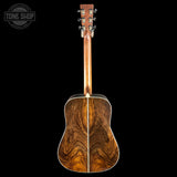 A classic acoustic guitar shown from the back, featuring a rich, dark wood grain finish on the backplate and neck, set against a solid black background with a Tone Shop watermark in the top-left corner.