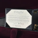 A Martin Custom Shop Certificate of Authenticity card displayed inside an open black Martin guitar case on a dark burgundy velvet surface.