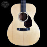 An acoustic guitar with a natural light wood finish and a dark pickguard, shown from the front against a solid black background. A 'TONE SHOP' watermark is visible in the top-left corner.