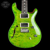 A green flamed maple electric guitar with a black body, silver hardware, and a black fretboard, shown against a black background with a Tone Shop watermark in the top left corner.