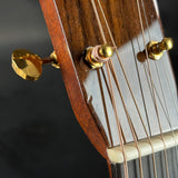 Close-up of a guitar's soundhole with wooden finish and gold tuning pegs.