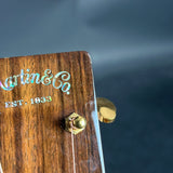 Close-up of a Martin & Co. guitar headstock with gold tuning pegs on a dark background