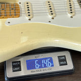 White electric guitar on a digital scale displaying weight