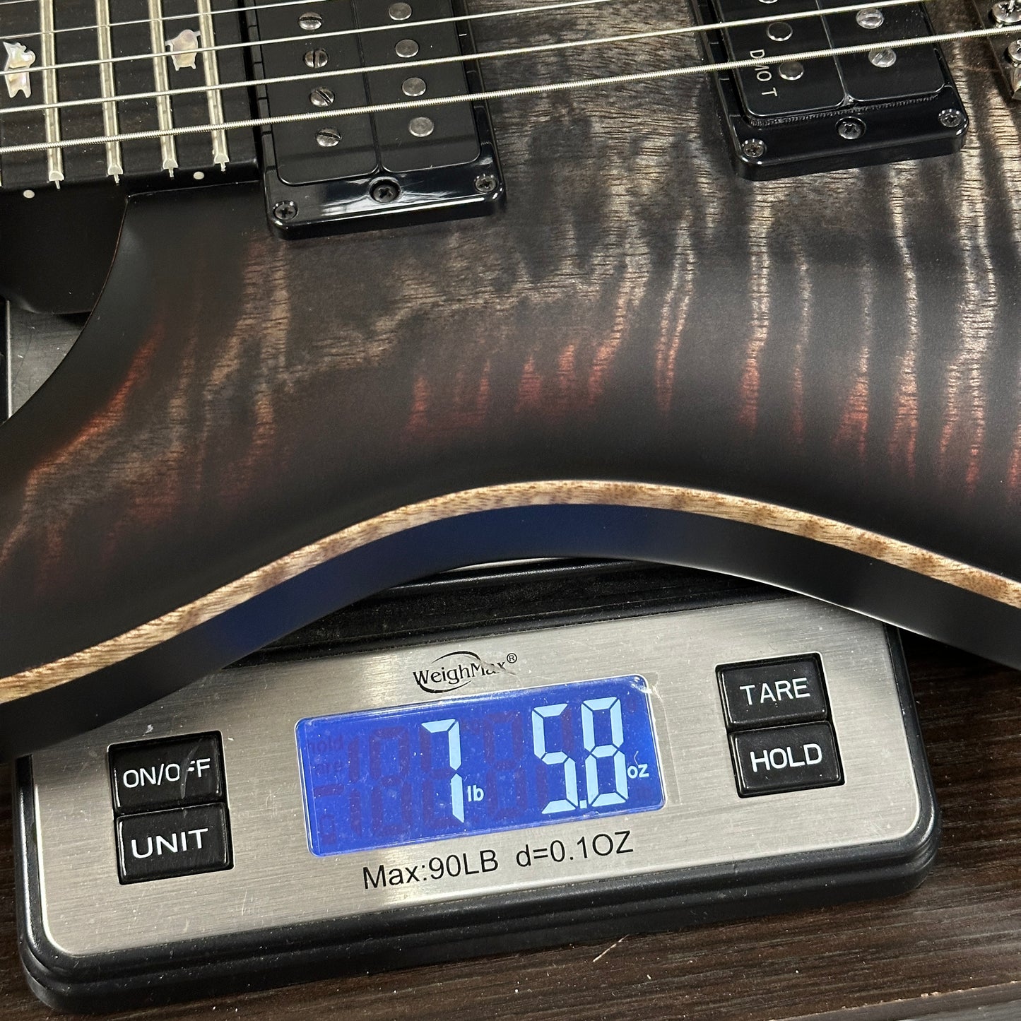 Guitar being weighed on a digital scale with a digital display showing weight.