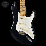 Black electric guitar with a white pickguard on a black background, featuring 'Tone Shop' branding.